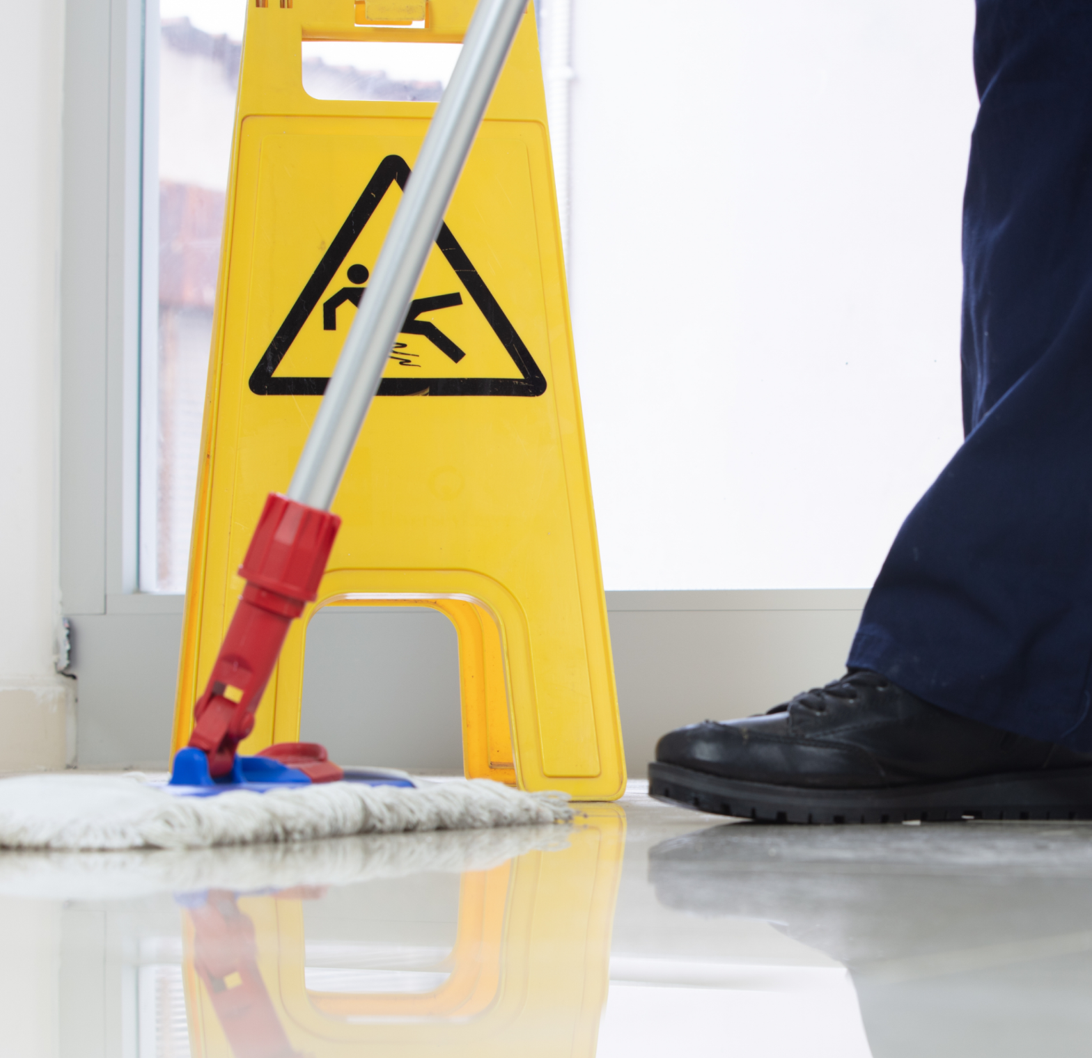 man cleaning the floor with mop and safety sign